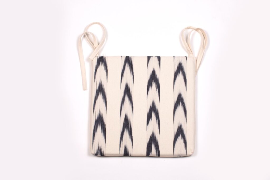 Cojín de silla con lazos confeccionado con tela mallorquina artesanal en crudo y negro de Teixits Vicens