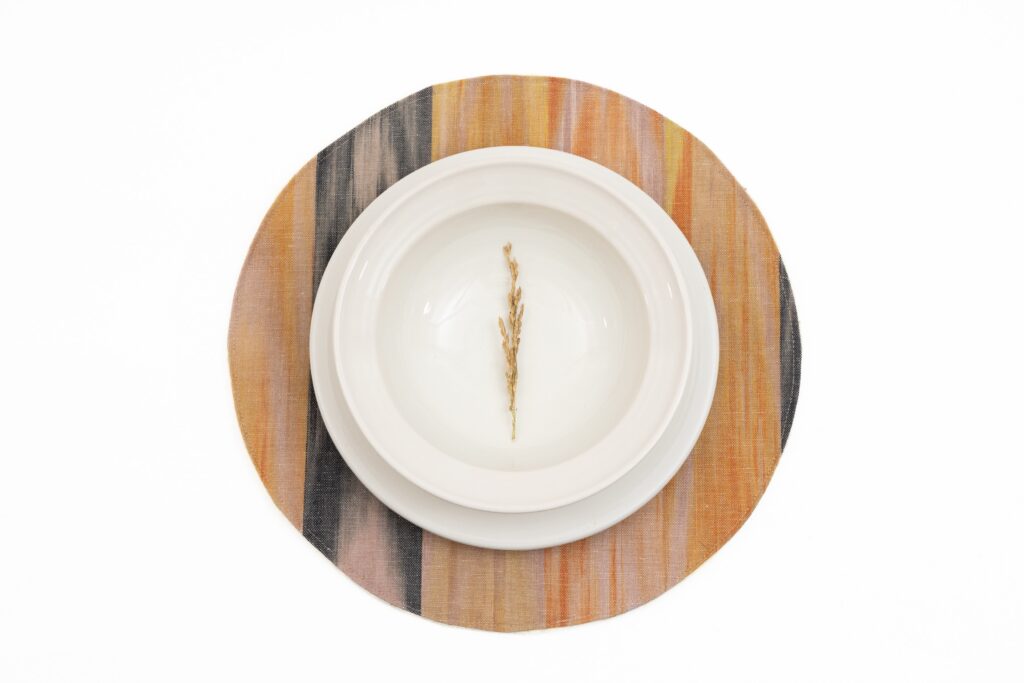 Salvamantel redondo de tela mallorquina con tonos tierra y negro de Teixits Vicens, estilo rústico para mesa