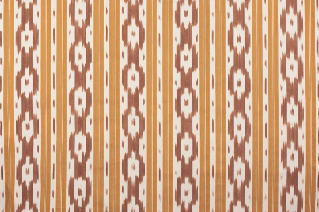 Tejido ikat mallorquín en tonos tierra y mostaza con diseño vertical de patrón tradicional y franjas