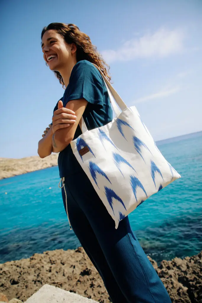 Modelo luciendo bolso artesanal de Teixits Vicens en entorno veraniego